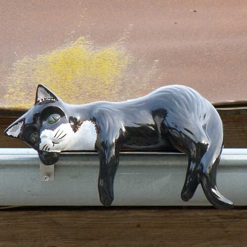 rinnenkatze liegend mit edelstahlhalterung auf einer dachrinne, glasiert in verschiedenen farben